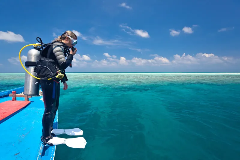 Plongeuse équipée prête à sauter dans une mer turquoise et calme
