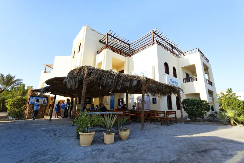 Façade d'un centre de plongée avec des personnes assises à l'ombre