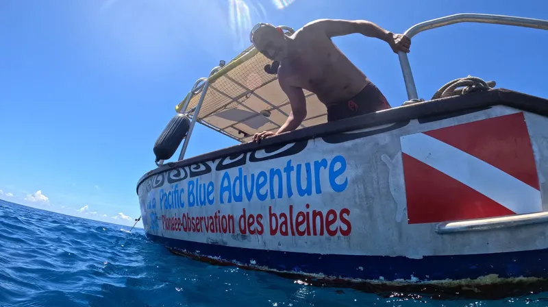 Homme en maillot de bain se penchant sur un bateau en mer