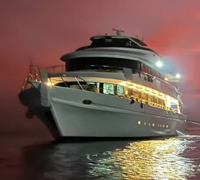Grand bateau de plongée blanc illuminé la nuit sur l'eau calme