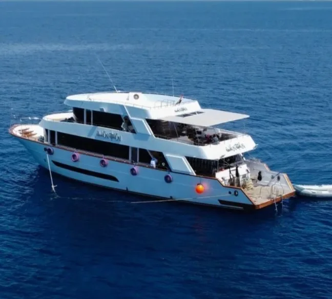 Grand bateau de plongée blanc navigue sur une mer bleue calme