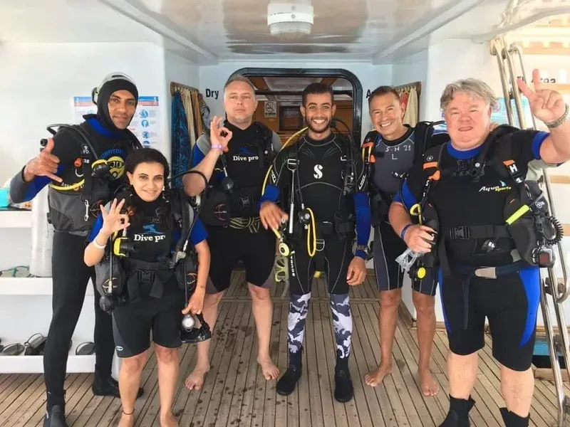 Groupe de plongeurs souriants sur le pont d'un bateau de plongée
