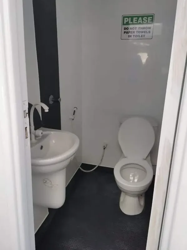 Intérieur de toilettes publiques avec lavabo et cuvette blanche