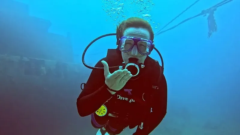 Plongeur souriant sous l'eau, faisant un signe avec sa main