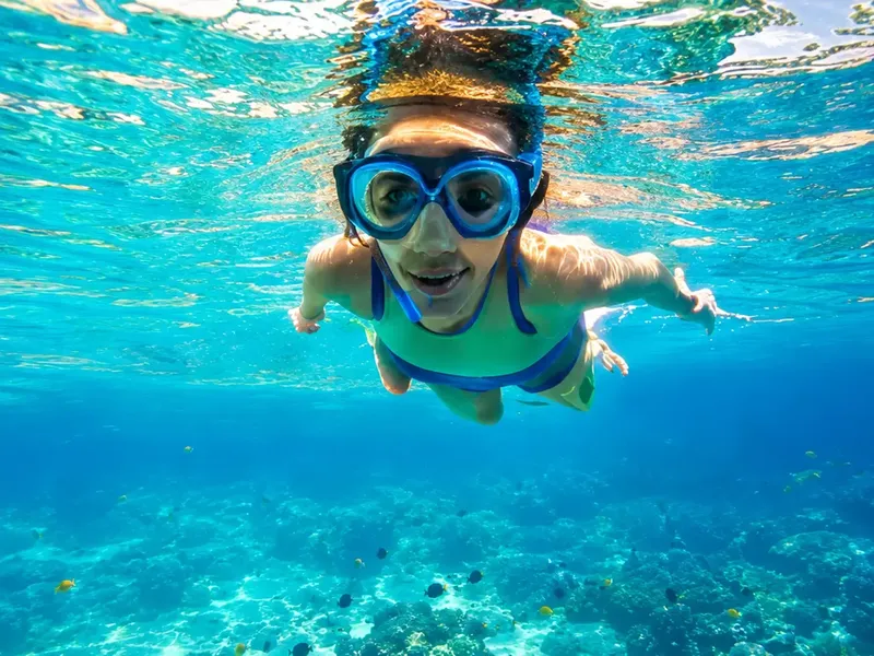 Jeune femme souriante nageant avec un masque et un tuba en mer
