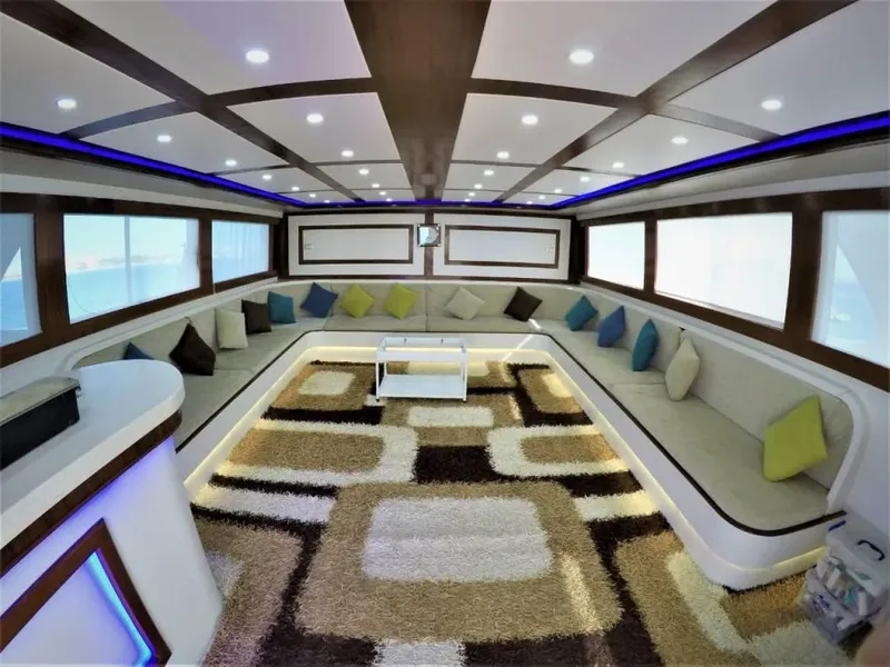 Intérieur lumineux d'un bateau de plongée avec banquettes et tapis colorés