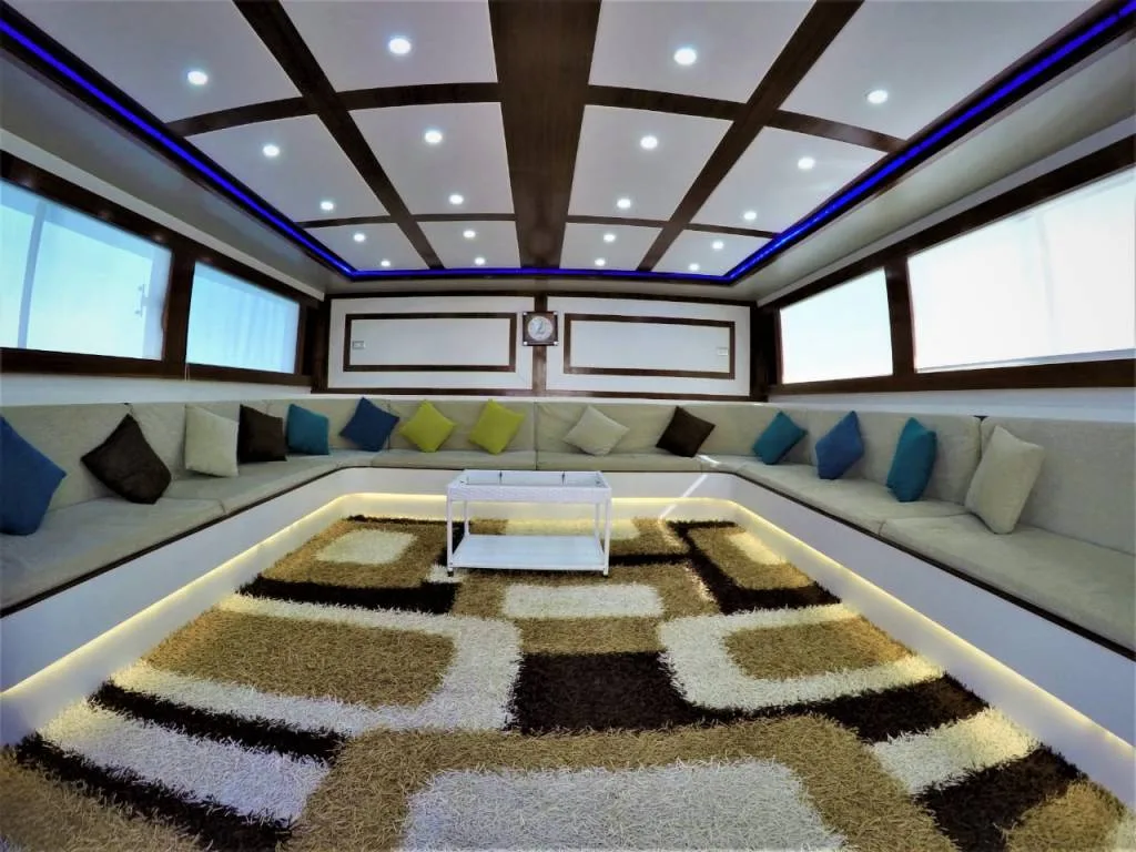 Salon de bateau avec banquettes, coussins colorés et tapis décoratif