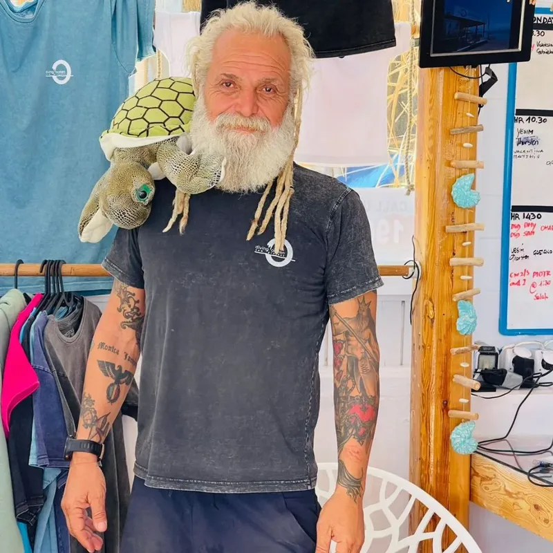 Homme souriant avec dreadlocks, tatouages et t-shirt dans un centre de plongée