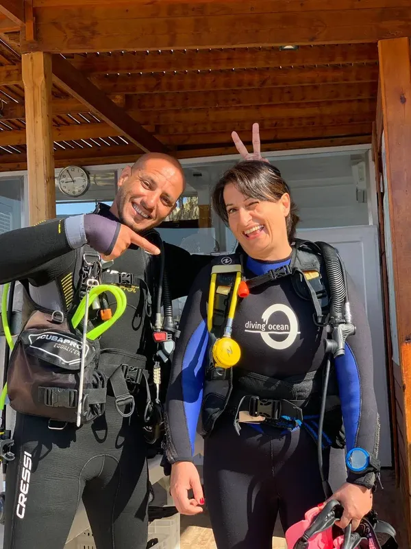 Deux plongeurs souriants équipés prêts pour une immersion en mer