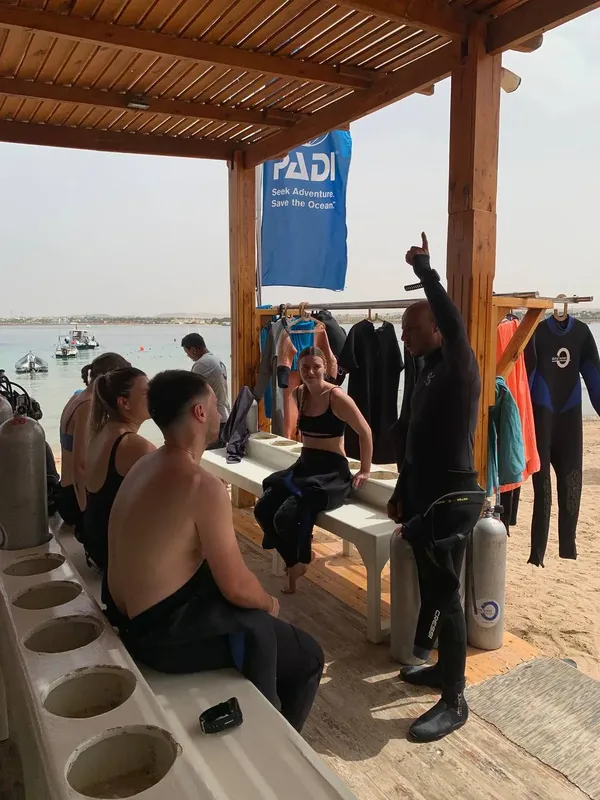 Groupe de personnes en combinaison de plongée, instructeur expliquant un briefing