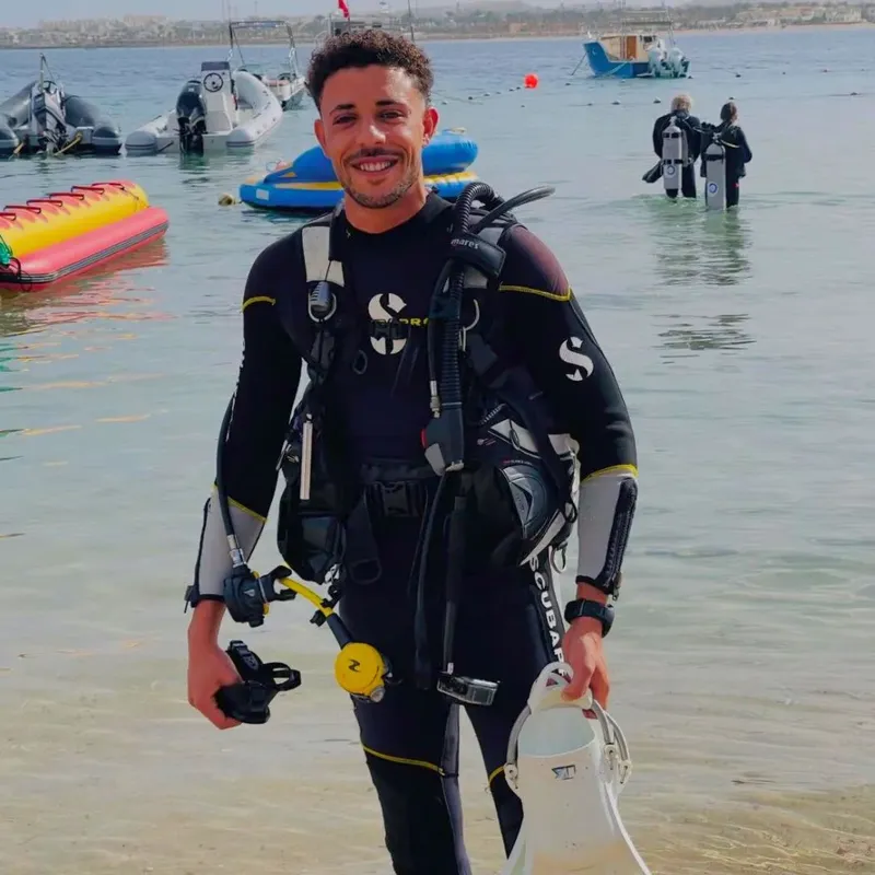 Plongeur souriant en combinaison complète, prêt à explorer les fonds marins