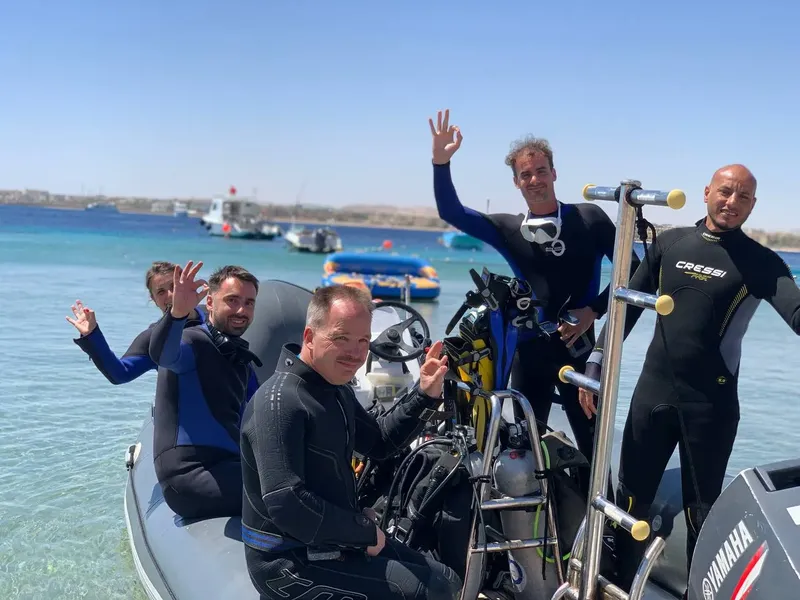 Plongeurs souriants sur un bateau pneumatique en mer, équipement visible