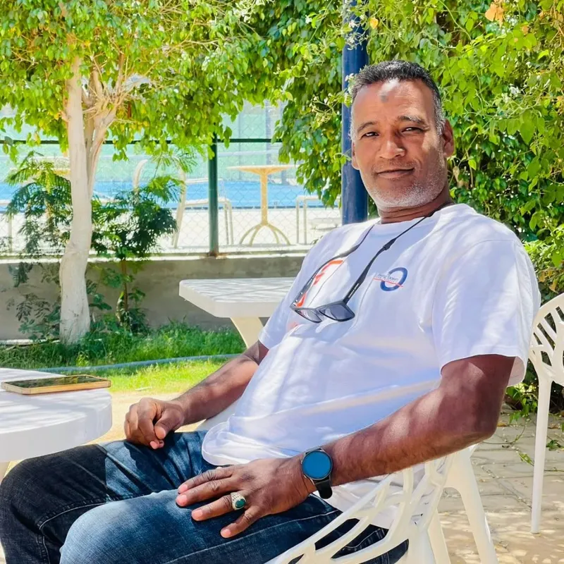 Homme souriant assis sur une chaise blanche en extérieur