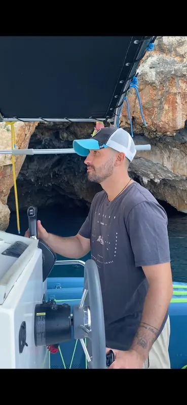 Homme conduisant un bateau en mer, portant une casquette et un t-shirt
