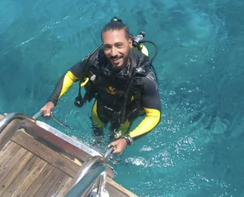Plongeur souriant sortant de l'eau depuis un bateau de plongée