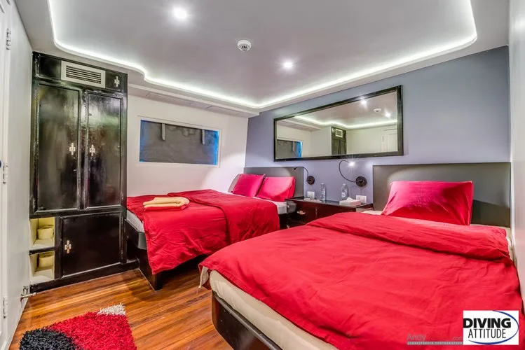 Chambre avec lits rouges et mobilier sombre, éclairage moderne et miroir