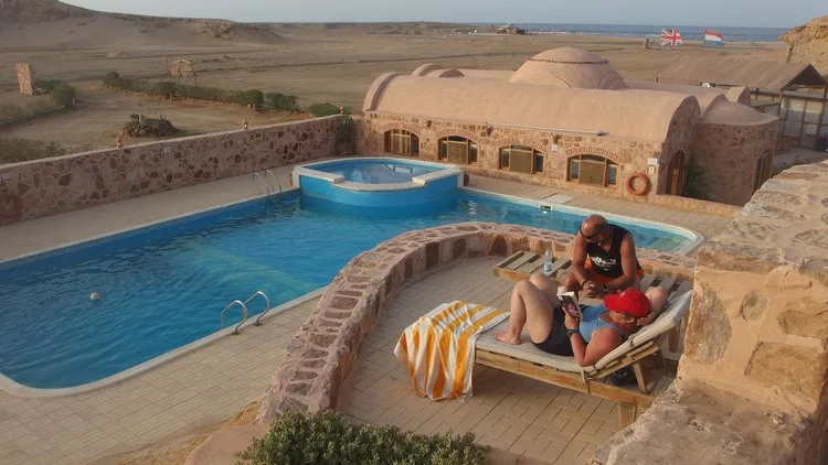 Vue d'une piscine et de bâtiments avec des personnes se relaxant