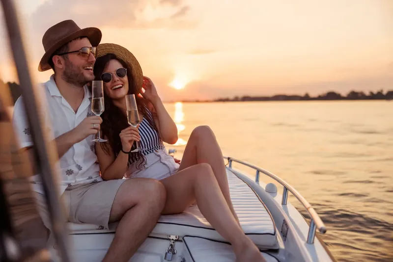 Couple souriant trinquant au champagne sur un bateau en mer