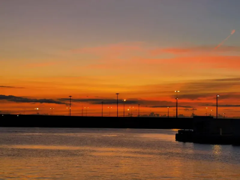 Coucher de soleil sur un port avec des lampadaires allumés