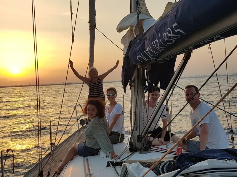 Groupe de personnes souriantes sur un voilier au coucher du soleil