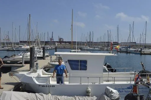 Homme debout sur un bateau de plongée dans un port ensoleillé