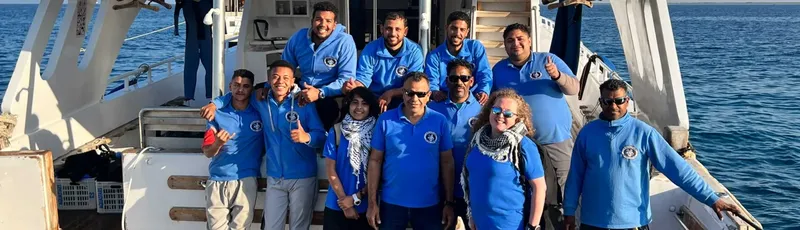 Equipe souriante sur un bateau de plongée en mer bleue