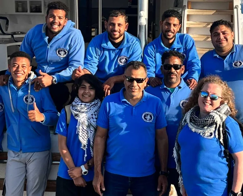 Groupe de personnes souriantes, portant des vêtements bleus, sur un bateau