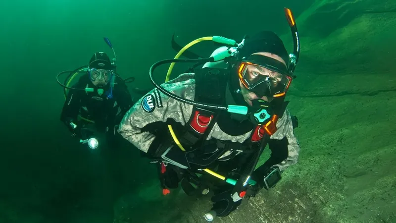 Deux plongeurs en combinaison explorent les fonds marins avec leurs lampes