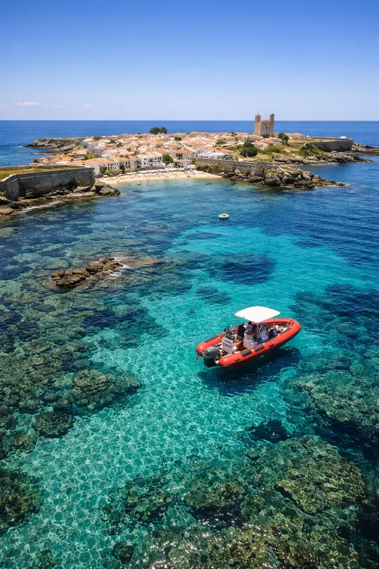 Bateau pneumatique rouge navigue dans une eau turquoise claire près d'une île