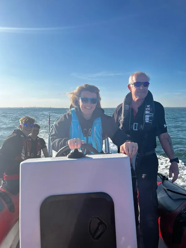 Personnes souriantes conduisant un bateau pneumatique sur une mer bleue