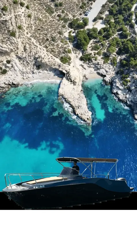 Bateau de plongée naviguant près d'une côte rocheuse et d'une eau turquoise