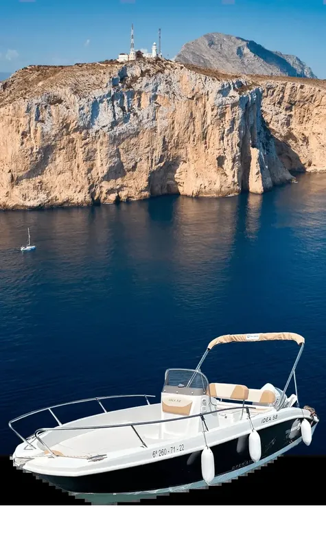 Bateau de plaisance blanc naviguant devant une falaise rocheuse ensoleillée