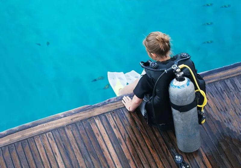 Plongeuse assise au bord d'un ponton, préparant son équipement