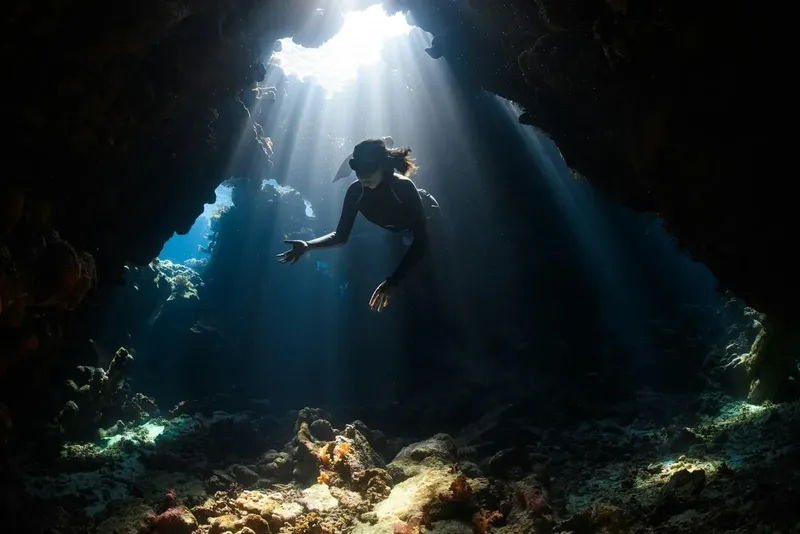 Apnée dans une grotte sous-marine, rayons de soleil, plongeuse explore