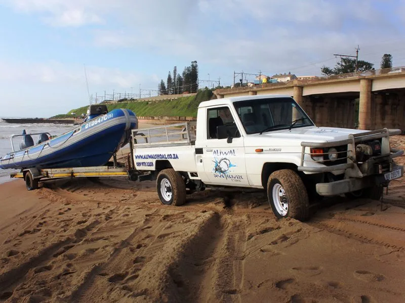 Remorque avec bateau de plongée sur une plage de sable clair