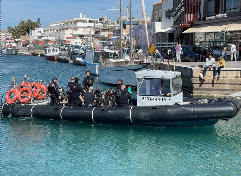 Plongeurs équipés montent à bord d'un bateau pneumatique dans un port