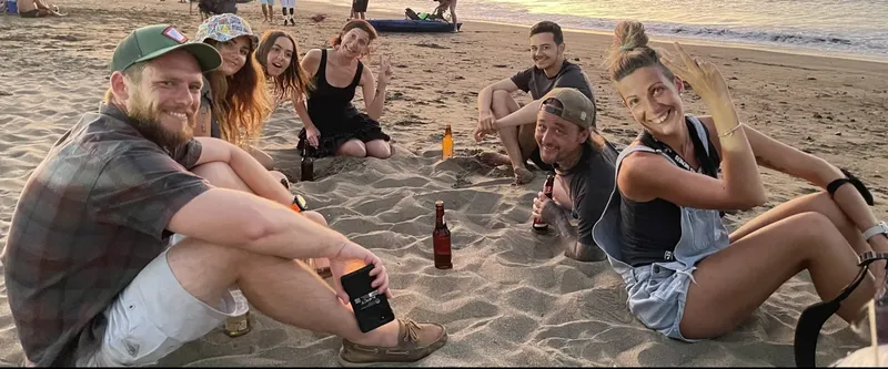 Groupe de personnes souriantes assises sur une plage de sable fin
