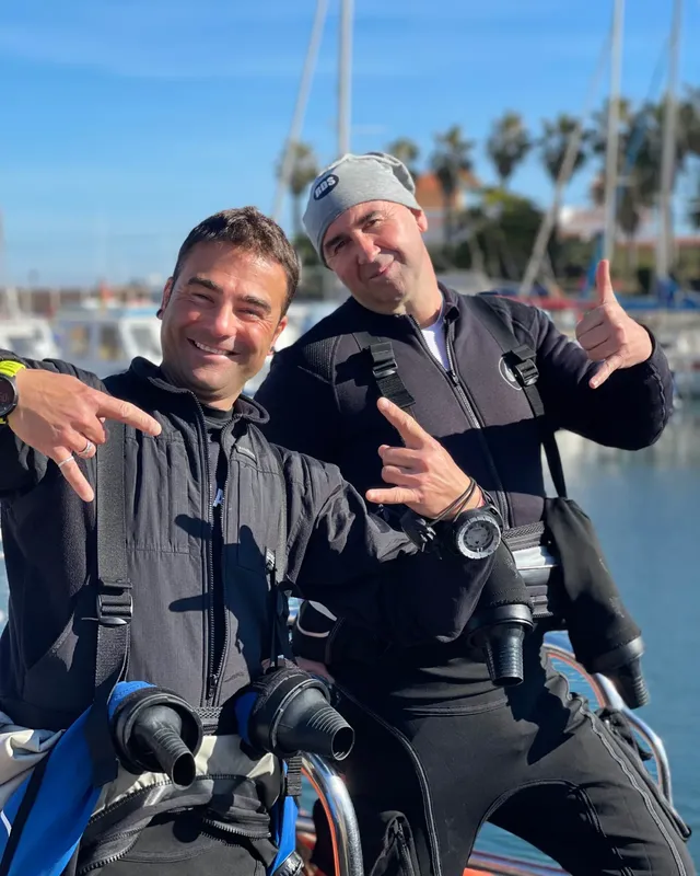 Deux plongeurs souriants en combinaison avec leur équipement complet