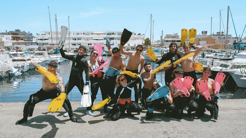 Groupe de plongeurs souriants posant avec leurs palmes sur un quai