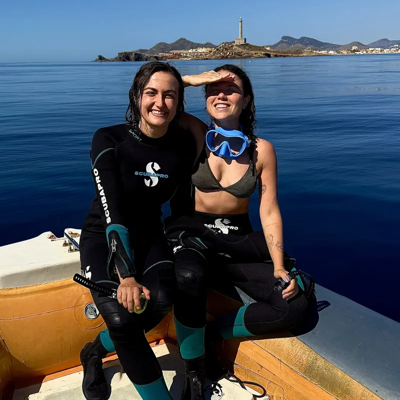 Deux plongeuses souriantes sur un bateau, équipées de gilets Scubapro