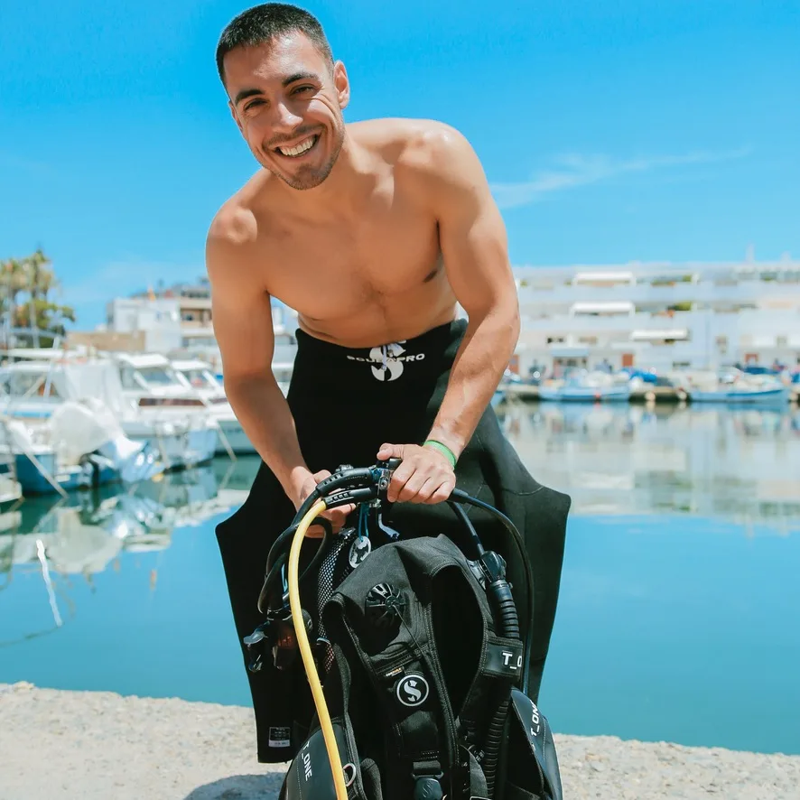 Plongeur souriant équipé prêt à plonger en bord de mer