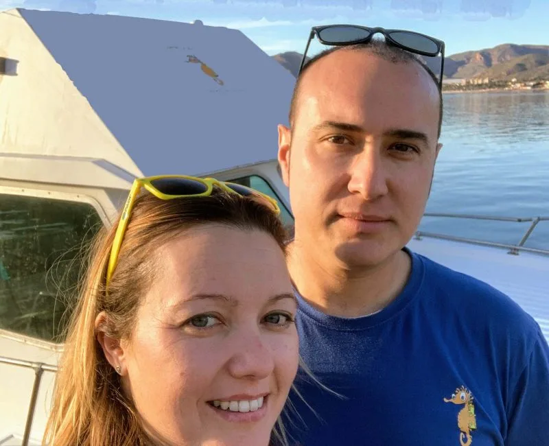 Deux personnes souriantes se prennent en photo devant un bateau