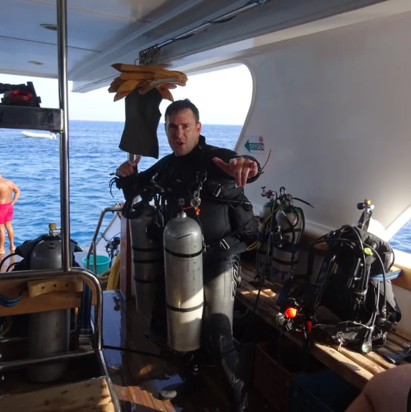 Plongeur en combinaison sur un bateau avec son équipement complet