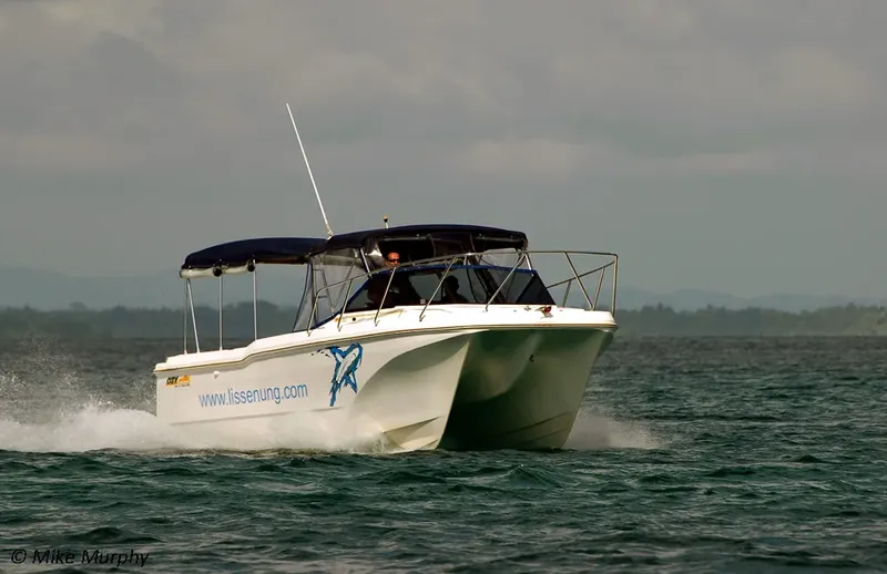 Bateau de plongée blanc navigue sur une mer agitée sous ciel gris