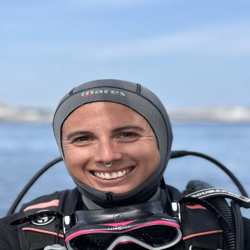 Plongeuse souriante avec masque et cagoule, équipement de plongée visible