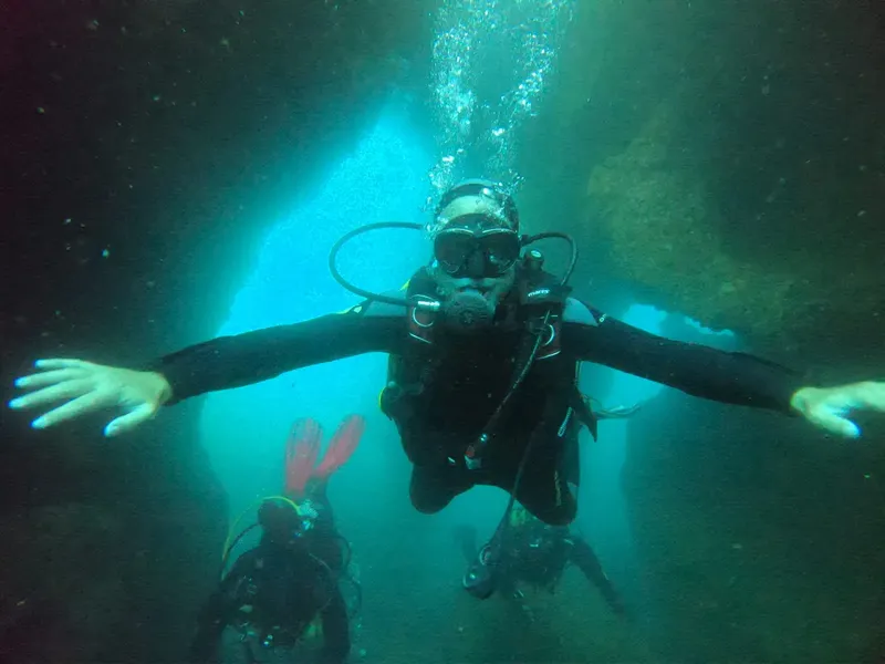 Plongeur souriant bras ouverts dans une grotte sous-marine éclairée