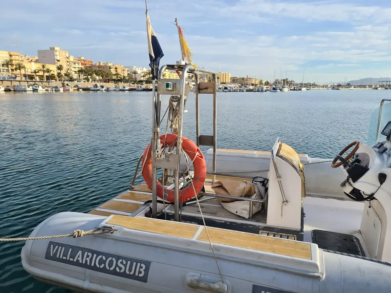 Bateau de plongée amarré dans un port ensoleillé avec ville en fond