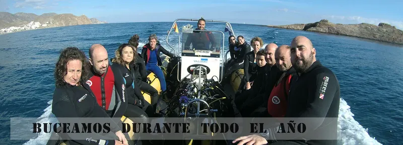 Groupe de plongeurs souriants à bord d'un bateau semi-rigide en mer