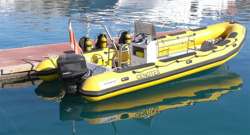 Bateau de plongée jaune amarré avec des bouteilles et un moteur hors-bord