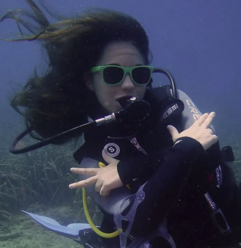 Plongeuse souriante avec lunettes de soleil, cheveux flottants, sous l'eau